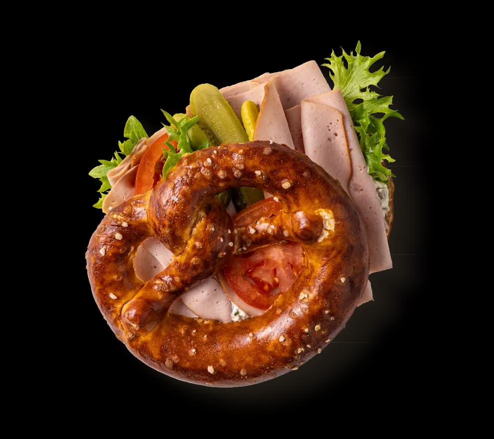 Ein Brezel mit Gurken und Fleischkäse belegt.